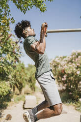 Junger Mann beim Training auf einer Stange in einem Park - FBAF01211