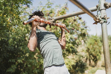 Young man during workout on a bar in a park - FBAF01212