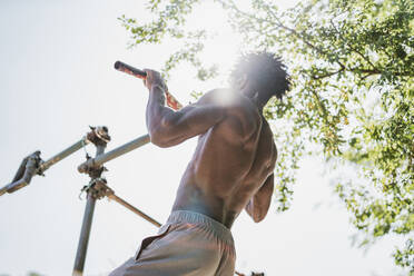 Young man during workout on a bar in a park - FBAF01213