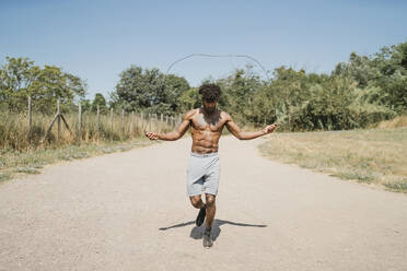 Junger Mann beim Seilspringen während des Trainings in einem Park - FBAF01228