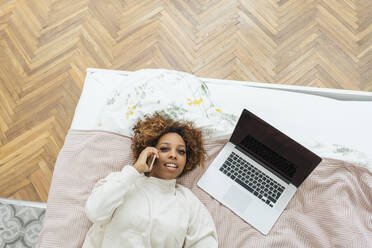 Junge Frau liegt im Bett und telefoniert - VPIF01919