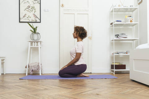 Junge Frau übt Yoga zu Hause, lizenzfreies Stockfoto