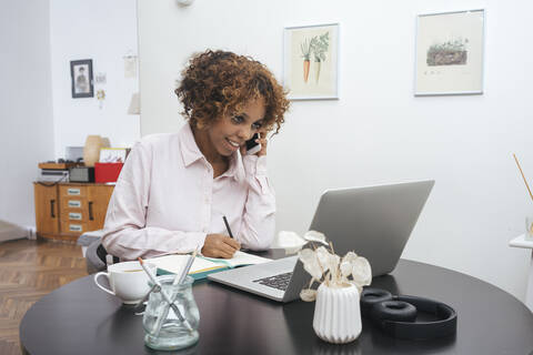 Young woman working at home talking on the phone stock photo