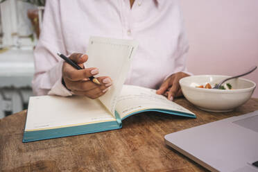 Close-up of young woman taking notes at table - VPIF01967