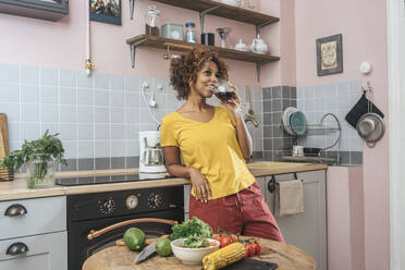 Smiling young woman drinking glass of red wine in kitchen - VPIF01983