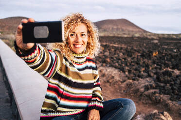 Porträt einer Frau, die einen bunten Pullover trägt und ein Selfie macht, Teneriffa, Spanien - SIPF02102
