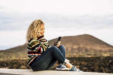 Porträt einer Frau, die einen bunten Pullover trägt und ein Smartphone benutzt, Teneriffa, Spanien - SIPF02105