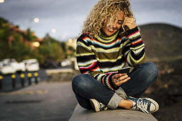 Porträt einer Frau, die einen bunten Pullover trägt und ein Smartphone benutzt, Teneriffa, Spanien - SIPF02106