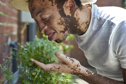 Young man with vitiligo with a hat smelling the plants stock photo