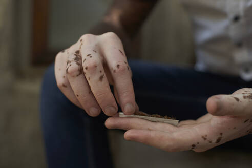 Close-up of young man with vitiligo rolling a cigarette - VEGF01347