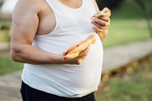 Man with beer belly holding sandwich - OCMF00986