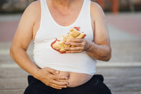 Mann mit Bierbauch hält Sandwich, lizenzfreies Stockfoto