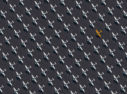 Luftaufnahme eines einzelnen orangefarbenen Flugzeugs, umgeben von ausschließlich weißen Flugzeugen - KNTF04124