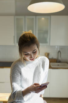 Junge Frau benutzt Smartphone zu Hause - JPTF00396