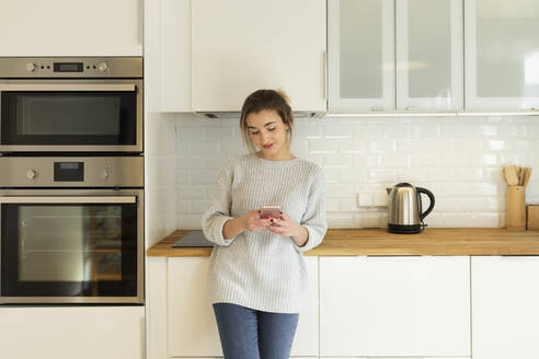 Junge Frau benutzt Smartphone zu Hause - JPTF00397