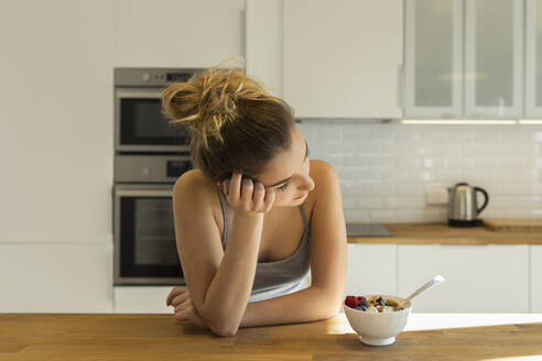 Weiblicher Teenager beim Frühstück in der Küche, Blick zur Seite - JPTF00403