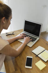 Female teenager using laptop at home - JPTF00407