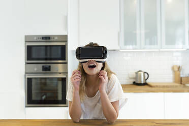 Weiblicher Teenager in der Küche mit VR-Brille - JPTF00418