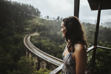 Sri Lanka, Provinz Uva, Demodara, Porträt einer erwachsenen Frau auf einem Balkon mit Blick auf die Nine Arch Bridge - DAWF01125