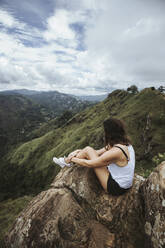 Sri Lanka, Uva Province, Ella, Female hiker sitting on boulder at Little Adams Peak - DAWF01130