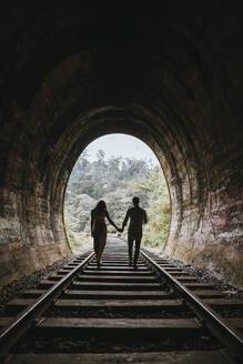 Sri Lanka, Provinz Uva, Demodara, Silhouette eines händchenhaltenden Paares beim Gang durch den Tunnel, der zur Nine Arch Bridge führt - DAWF01136