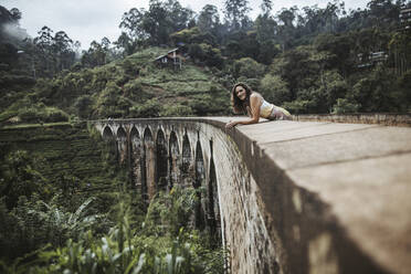 Sri Lanka, Provinz Uva, Demodara, Porträt einer erwachsenen Frau, die sich an die Nine Arch Bridge lehnt - DAWF01141