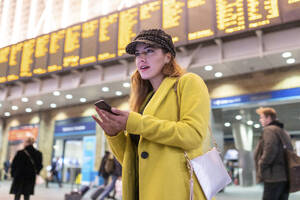 Frau am Bahnhof überprüft ihr Smartphone - WPEF02434