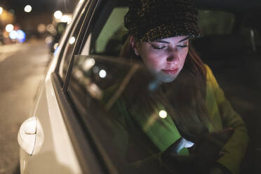 Frau auf dem Rücksitz eines Autos in der Stadt bei Nacht - WPEF02446