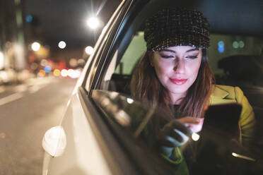 Frau auf dem Rücksitz eines Autos in der Stadt bei Nacht - WPEF02449