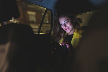Frau auf dem Rücksitz eines Autos in der Stadt bei Nacht - WPEF02451
