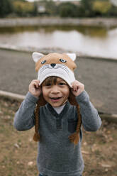 Portrait of little boy putting on woolly hat - GRCF00030