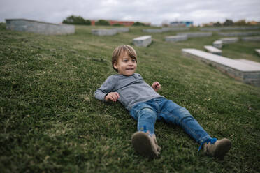 Portrait of smiling little boy lying on a meadow - GRCF00042