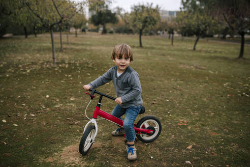 Porträt eines kleinen Jungen mit Laufrad auf einer herbstlichen Wiese - GRCF00044