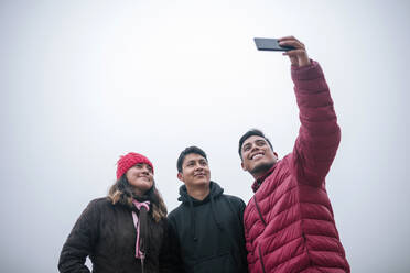 Junge mexikanische Freunde machen ein Selfie an einem nebligen Tag - GRCF00048