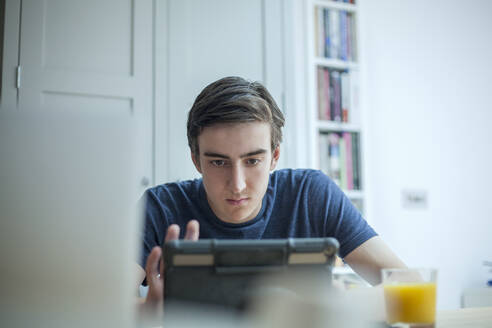 Konzentrierter Teenager, der zu Hause ein Tablet benutzt - AJOF00080