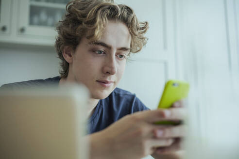 Young man using smartphone at home - AJOF00081