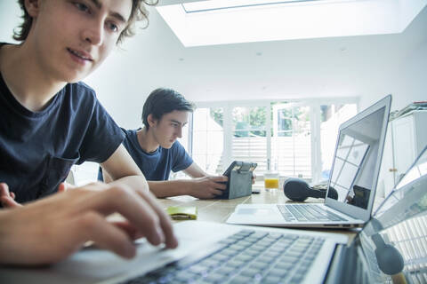 Zwei Teenager benutzen Laptop und Tablet auf dem Tisch zu Hause, lizenzfreies Stockfoto