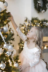 Porträt eines blonden kleinen Mädchens beim Schmücken des Weihnachtsbaums - EYAF00800