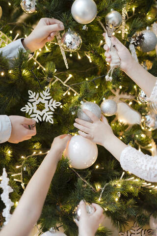 Crop-Ansicht von Kinderhänden beim Schmücken des Weihnachtsbaums, lizenzfreies Stockfoto