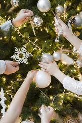 Crop view of children's hands decorating Christmas tree - EYAF00801