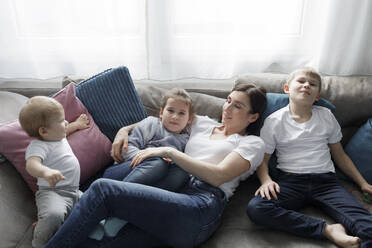 Family relaxing on couch in living room at home - KMKF01156