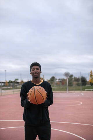 Teenager hält Basketball, lizenzfreies Stockfoto