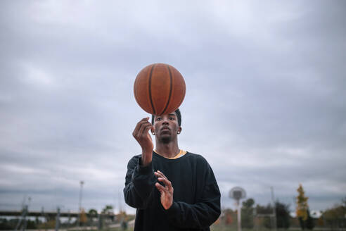 Teenager balanciert Basketball auf seinem Finger - GRCF00054