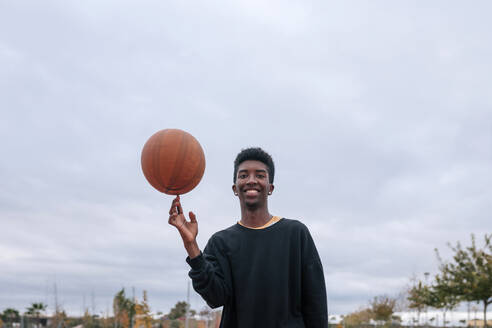 Teenager balancing basketball on his finger - GRCF00055