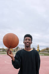 Teenager balanciert Basketball auf seinem Finger - GRCF00056