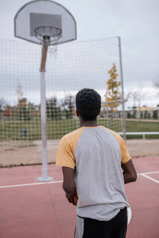 Rückansicht eines Basketball spielenden Teenagers, lizenzfreies Stockfoto