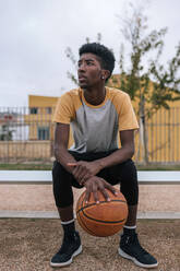Teenager holding basketball and looking sideways - GRCF00072