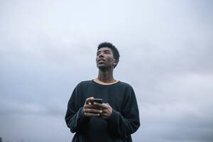 Teenager, der sein Smartphone benutzt, Blickwinkel niedrig - GRCF00080