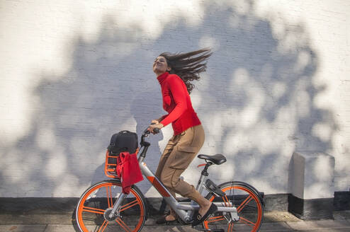 Carefree young woman riding a rental bike - AJOF00098