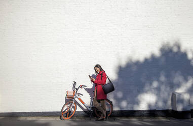 Young woman using rental bike with smartphone app l - AJOF00101